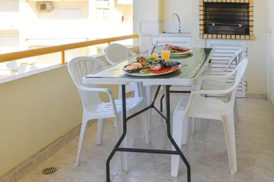 a table with white chairs and a plate of food on it at Vila Atlântida - Vilamoura-Quarteira Holiday Home - Beach at 250 mts in Quarteira