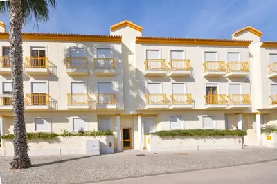 an apartment building with balconies and a palm tree at Vila Atlântida - Vilamoura-Quarteira Holiday Home - Beach at 250 mts in Quarteira