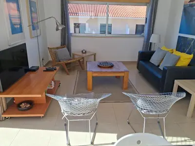 a living room with a couch and a table and chairs at Modern apartment with sunny south facing terrace in Albufeira