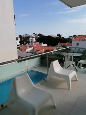 a balcony with two white chairs and a table at Modern apartment with sunny south facing terrace in Albufeira