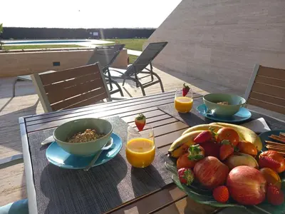 a table with a bowl of fruit and two cups of orange juice at Prestige & Nature Apartment in Laguna Village in Quarteira