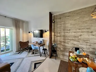 a living room with a wooden wall and a table at Albufeira Stylish 1 by Homing in Albufeira