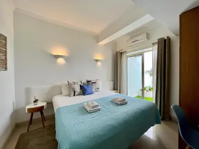 a bedroom with a bed with a blue blanket and a window at Albufeira Stylish 1 by Homing in Albufeira