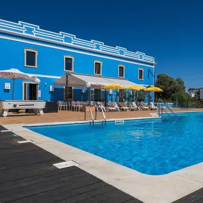 a blue building with a pool and chairs and umbrellas at Amazing 2-Bedroom Appartment with big terrace! in Albufeira
