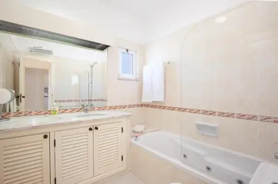 a bathroom with a tub and a sink and a mirror at Amazing 2-Bedroom Appartment with big terrace! in Albufeira