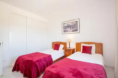 two beds in a white room with red sheets at Amazing 2-Bedroom Appartment with big terrace! in Albufeira