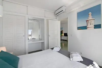 a white bedroom with a bed and a painting on the wall at Ocean View Apartment Hakuna Matata in Albufeira