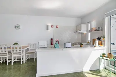 a white kitchen with a counter and a table at Ocean View Apartment Hakuna Matata in Albufeira