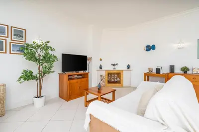 a living room with a white couch and a tv at Vilamoura City Centre Flat in Vilamoura