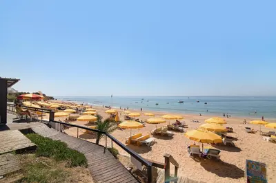a beach with yellow umbrellas and people in the ocean at Ouramar Apartment in Areias de São João