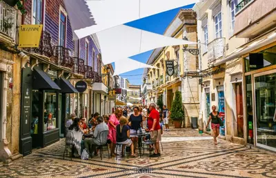 a group of people sitting at tables in a street at Casa AL Reis in Faro