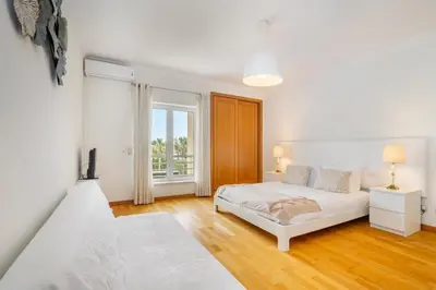 a white bedroom with a bed and a window at WHome Family Holidays w/ S-Pool, AC, Elevator & Garage in Quarteira