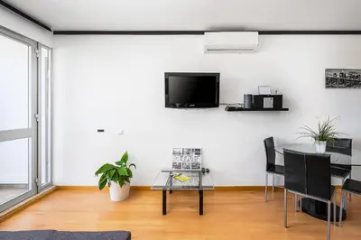 a living room with a table and a tv on a wall at Apartamento Portugal in Quarteira
