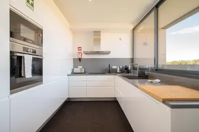a kitchen with white cabinets and a large window at Apart L'Orange in Vilamoura