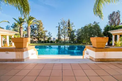 a swimming pool in a villa with palm trees at Cypress Villa in Albufeira