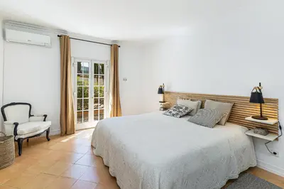 a white bedroom with a bed and a chair at Cypress Villa in Albufeira