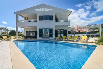 a villa with a swimming pool in front of a house at Villa Alfazema in Albufeira