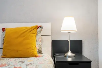 a bed with a yellow pillow and a lamp on a table at Villa at the beach in Vale do Lobo