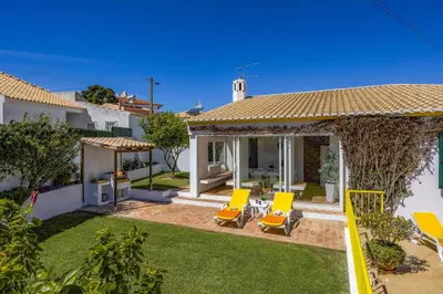 a villa with a yard with two yellow chairs at Villa Pinheiro Oura by Villa Plus in Albufeira