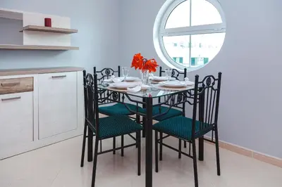 a dining room table with chairs and a round mirror at Tatiana 1 bedroom apartment in Albufeira
