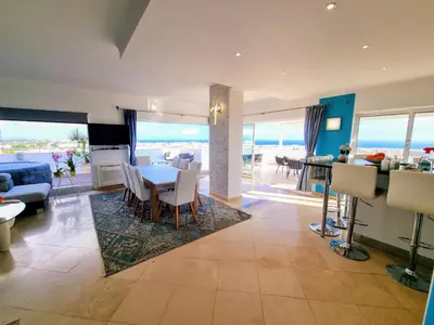 a dining room and living room with a view of the ocean at Penthouse Rentalbufeira in Albufeira