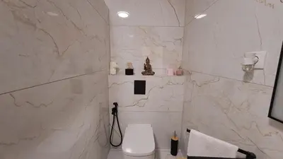 a bathroom with a toilet and a marble wall at Albufeira Oura Beach Apartment in Albufeira