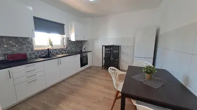 a kitchen with white cabinets and a table and chairs at Albufeira Oura Beach Apartment in Albufeira