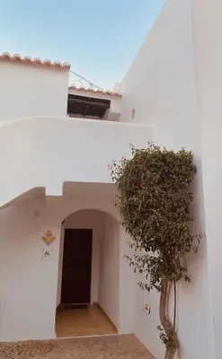 a white building with a tree next to a doorway at Albufeira Praia São Rafael Sun Apartment in Albufeira