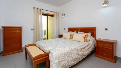 a bedroom with a bed with wooden furniture and a window at Parque Atlântico Apartment T1 in Quarteira