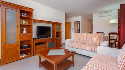 a living room with a couch and a tv at Parque Atlântico Apartment T1 in Quarteira
