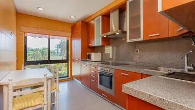 a kitchen with wooden cabinets and a counter top at Parque Atlântico Apartment T1 in Quarteira