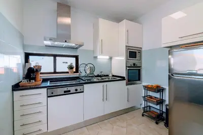 a white kitchen with white cabinets and a window at Holiday 1 Bed Apartment with pool in Albufeira in Albufeira