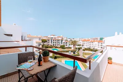 a balcony with a table with a glass of wine at Holiday 1 Bed Apartment with pool in Albufeira in Albufeira