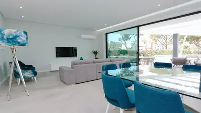 a living room with a glass table and blue chairs at Villa Waterfall - Clever Details, luxury, 5min walking from the center in Vilamoura