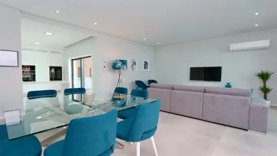 a dining room with a glass table and blue chairs at Villa Waterfall - Clever Details, luxury, 5min walking from the center in Vilamoura