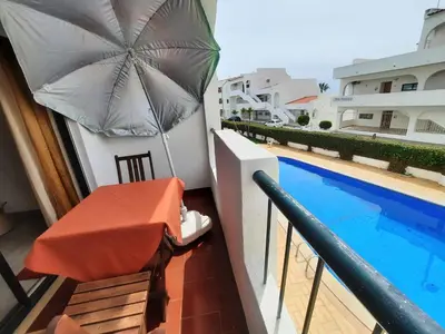 a balcony with a table and an umbrella next to a swimming pool at Casa Cerro Sol in Albufeira