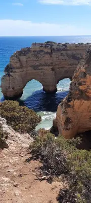 an arch in a rock formation in the ocean at Rural Peace in the Algarve - Private Room with kitchenette and bathroom in Aldeia dos Matos