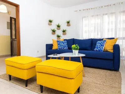 a living room with a blue couch and two yellow stools at Villa Bel Mar by Stay ici Algarve Holiday Rental in Guia