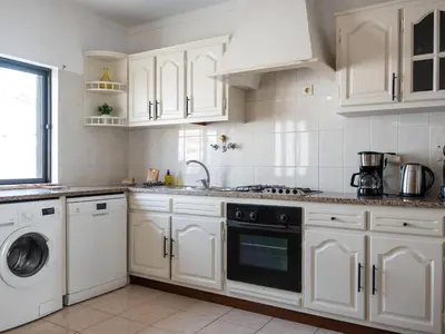 a kitchen with white cabinets and a washer and dryer at Villa Bel Mar by Stay ici Algarve Holiday Rental in Guia