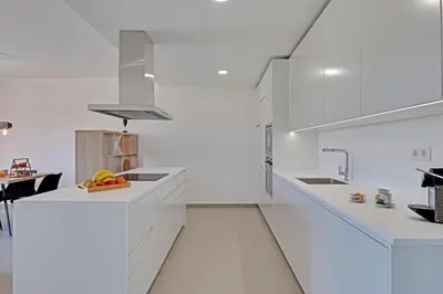 a white kitchen with white cabinets and a sink at Apartamento Vista Jardim by Portucasa in Albufeira