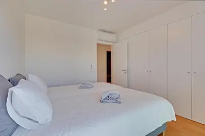 a bedroom with a white bed with towels on it at Apartamento Vista Jardim by Portucasa in Albufeira