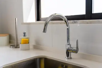 a kitchen sink with a faucet next to a window at APARTAMENTO TROPICANA in Quarteira