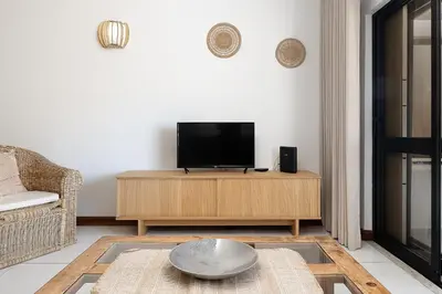 a living room with a flat screen tv on a wooden cabinet at APARTAMENTO TROPICANA in Quarteira