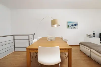 a dining room with a wooden table and white chairs at Apartamento Janelas Oceano - Vilamoura in Quarteira