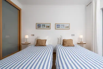 two beds in a room with blue and white stripes at Apartamento Janelas Oceano - Vilamoura in Quarteira