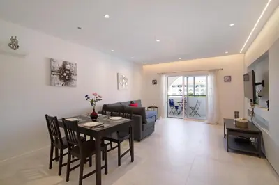 a dining room and living room with a table and chairs at Apartamento Max Tropical by Sunnyway in Albufeira