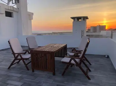 a table and chairs on a rooftop with the sunset at Bmar in Quarteira