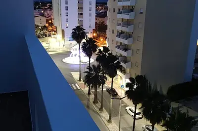 a view of a city street with palm trees at night at Bmar in Quarteira