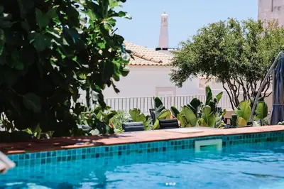 a pool with chairs and trees next to a building at Old Fisherman's Corner 12 - Centro Old Town Albufeira in Albufeira