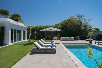 a pool with two lounge chairs and an umbrella at Villa Allegra - Quinta do Lago in Almancil